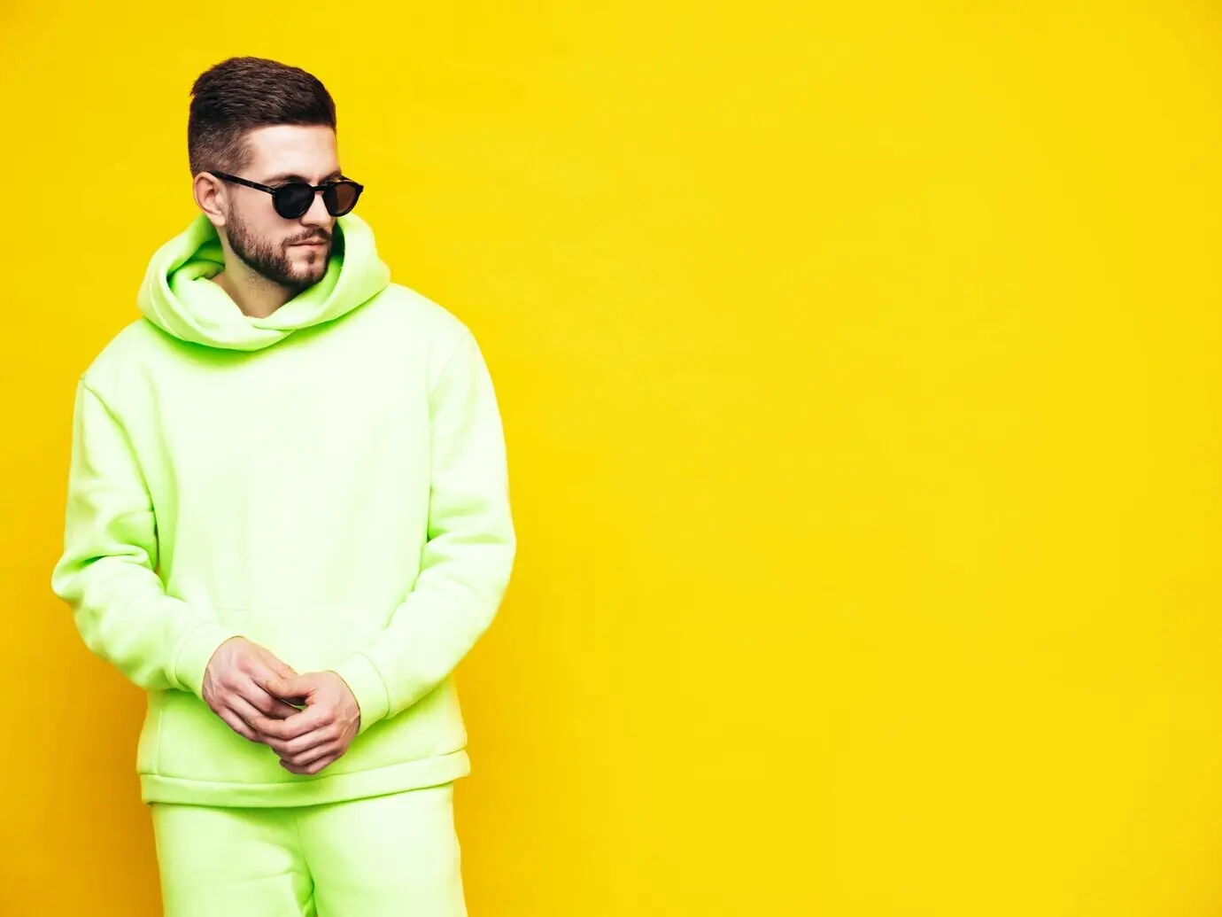 Porträt eines gutaussehenden, selbstbewussten Models: ein sexy, stilvoller Mann in einem gelben Hoodie ohne Logo. Mockup für Bekleidungs-Branding, Designvorlage für legere Sportbekleidung. Männliches Fashion-Model im Studio isoliert.